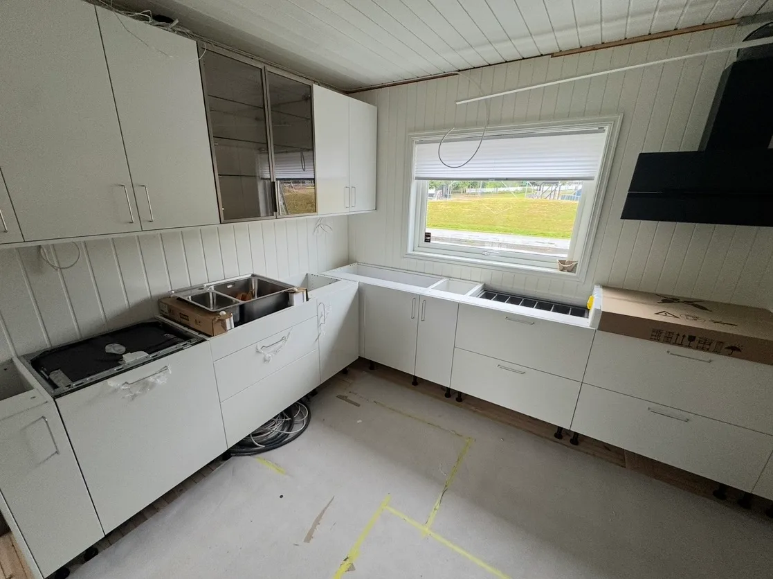 Utsnitt av et kjøkken med hvite skaper og benkeplater før montering